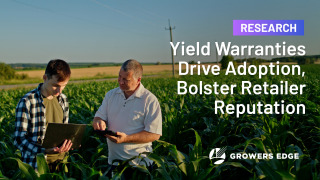 Two white men in a corn field. Both are looking down; one is pointing to a screen. The text reads "Research: Yield Warranties Drive Adoption, Bolster Retailer Reputation"