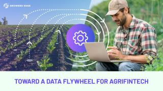A split image: on the left, a field of row crops. On the right, a white man working on a laptop with a field in the background. Superimposed is a cog icon with white circles spiraling outward. Text reads "Toward a Data Flywheel for Agrifintech"